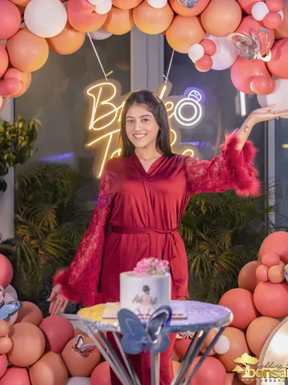 The bride-to-be posing happily with her cake and the festive party decorations.