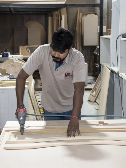 A craftsman carefully assembles a wooden frame in our workshop. This image highlights the hands-on approach and skill involved in creating the foundational structure of our bespoke furniture.