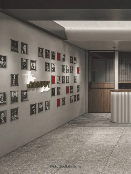 The entrance corridor of The Comedy Theatre, featuring a wall of fame with portraits of comedians. The clean, minimalist design with terrazzo flooring and a fluted reception desk sets a professional yet creative tone.