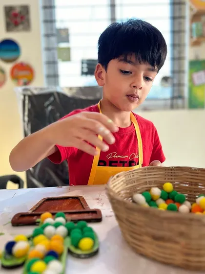 Next comes the fun part: adding the pom-poms. This little guy is carefully selecting and placing the fluffy balls into the basket.