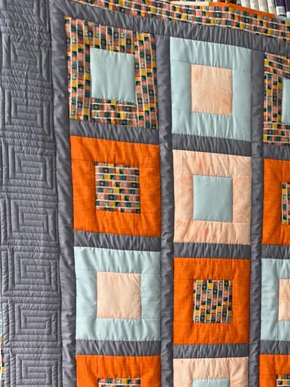 This close-up shows the "ruler work" on the border of a quilt, creating a precise, geometric Greek key pattern.
