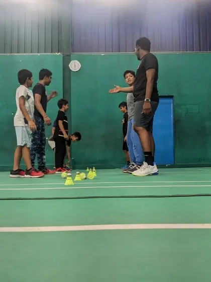 A coach explaining a drill to a group of young players during a match day warm-up. Even on competition days, learning and improvement are the focus.