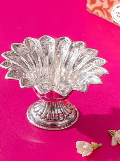 An ornate peacock-shaped silver diya (oil lamp), a beautiful and auspicious gift that guests can use in their homes.