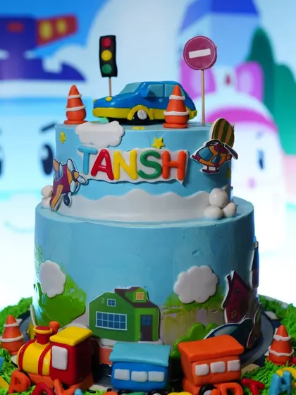 A close-up of a custom-designed cake for a transportation theme party. This two-tier cake is decorated with cars, trains, and traffic signs, perfectly matching the event's decor.