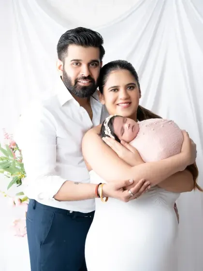 A classic family portrait with a new baby. The parents' joyful smiles and gentle hold create a powerful image of love and new beginnings.