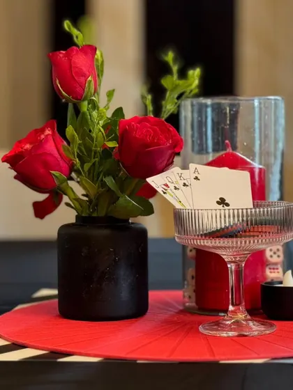 An artful shot of the casino centerpiece, with a royal flush of clubs displayed in a coupe glass, surrounded by red roses and a red candle.