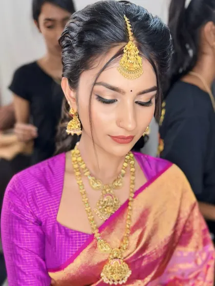 A stunning look for a young client. The makeup is kept fresh and radiant, with soft gold eyeshadow and a neutral lip to complement her bright pink saree and traditional gold jewelry.