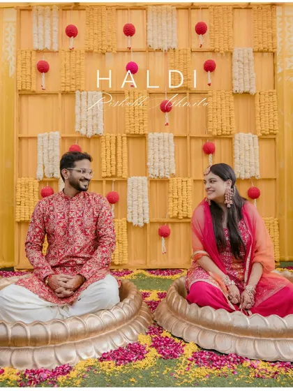 A serene portrait of the couple seated in beautiful lotus-shaped seats before the haldi rituals begin. The vibrant yellow decor and their happy expressions set the stage for a beautiful celebration.