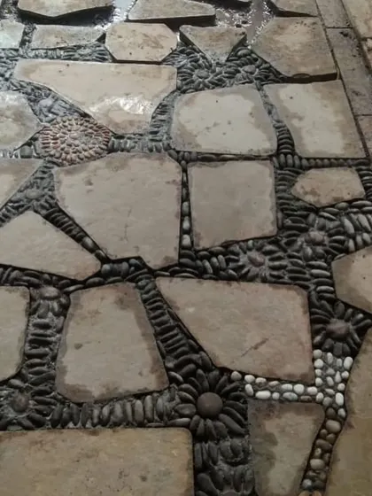 A creative and durable pathway made from irregular flagstones, with decorative pebbles filling the gaps in floral patterns.