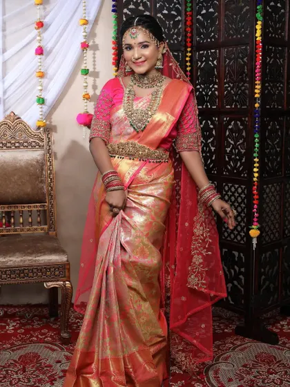 This bride looks absolutely majestic in her pink saree and full temple jewellery set. The matching waist belt and headpiece complete the royal look.