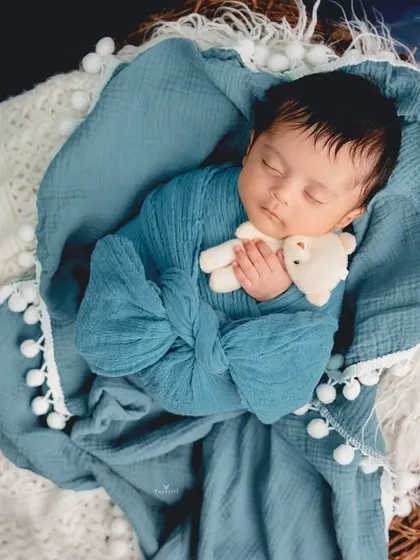 A pop of color in this newborn portrait. The baby is swaddled in a beautiful blue wrap, sleeping soundly in a cozy basket.