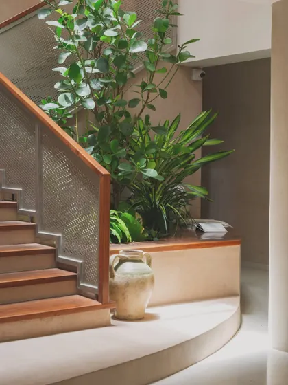 The entryway of this home is designed around a central staircase and a planter bed, reminiscent of a traditional courtyard. The wooden archway frames the view, creating a layered and welcoming first impression.