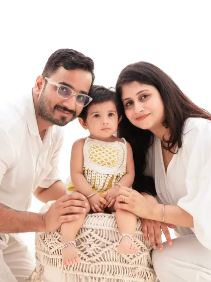 A classic family portrait in coordinated white outfits. The clean, minimalist setup allows the family's connection and happiness to be the main focus.