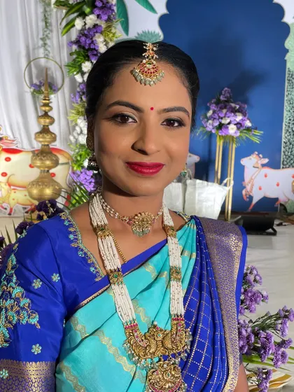 A happy client at a family function. The makeup is bright and celebratory, with a classic red lip and beautiful pearl jewelry.