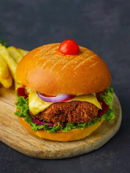 A close-up of a burger and fries, focusing on the crispy patty and fresh toppings.