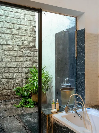 A look into the open-air shower space, with its stone walls and greenery, offering a unique and refreshing experience.