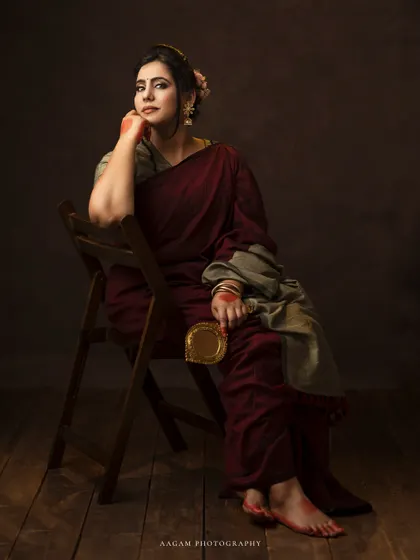 Holding a brass mirror, she looks thoughtful and poised. This portrait is a beautiful blend of tradition and fine art.