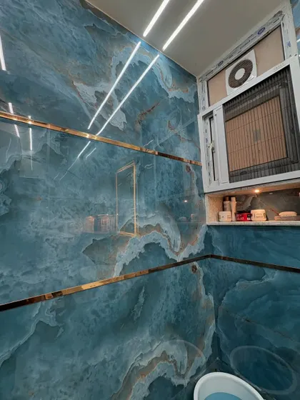 This image showcases the dramatic effect of large-format blue marble tiles with gold accents. The built-in niche next to the window provides convenient storage space.