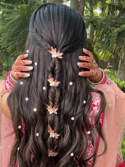 This half-up, half-down braided hairstyle is perfect for an engagement or sangeet. We'll teach you how to create the delicate central braid and place pearl and floral accessories for a soft, romantic vibe.