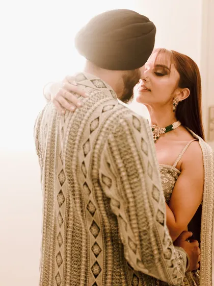 An intimate and beautifully backlit portrait. The soft flare of light envelops the couple, creating a dreamy and romantic atmosphere that highlights their close embrace.
