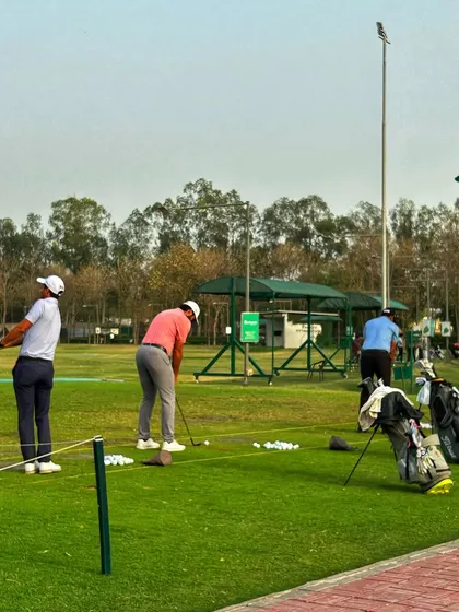 Three golfers practice in a line on a beautiful day, showcasing the camaraderie of the range.