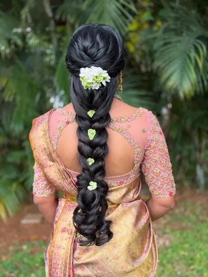 A simple yet elegant braid adorned with fresh white flowers and green leaves. This minimalist approach is perfect for a bride who loves understated beauty.