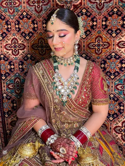 This bride looks serene and beautiful. The makeup is soft yet defined, with a focus on flawless skin and highlighting her features to match her ornate wedding attire.