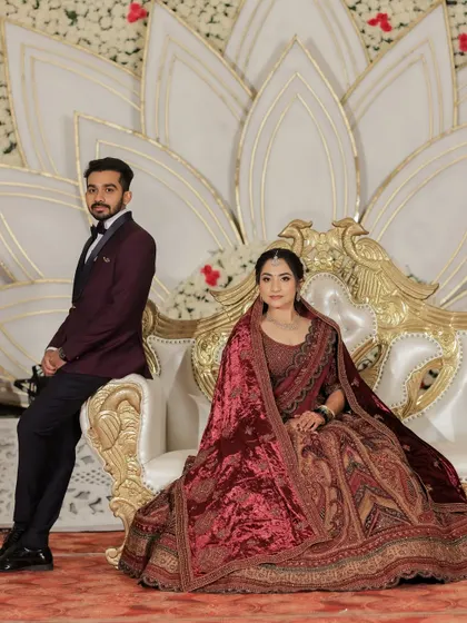 The couple seated on their grand reception stage. The bride's makeup is designed to look stunning in professional photography.