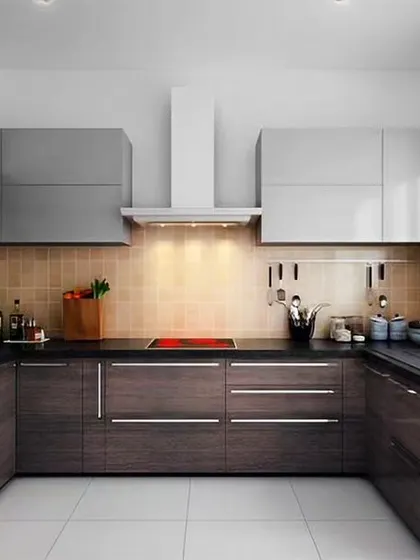 A U-shaped kitchen with dark wood-grain base cabinets and grey uppers. The stainless steel refrigerator and induction cooktop add to the modern, functional feel.