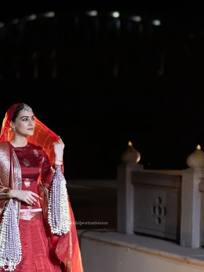 A beautiful, softly lit portrait of Kriti Sanon in her red lehenga. This shot feels intimate and captures her elegance against the backdrop of the illuminated bridge.