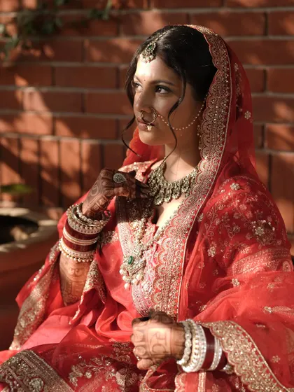 A stunning portrait of a bride in her wedding attire. Her hands, adorned with dark, intricate mehendi, complete the traditional look.