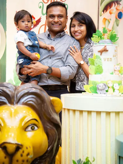 A precious family moment with the birthday boy, Ved, and his amazing jungle-themed cake. The lion prop in the foreground adds a fun, layered element to the photo.