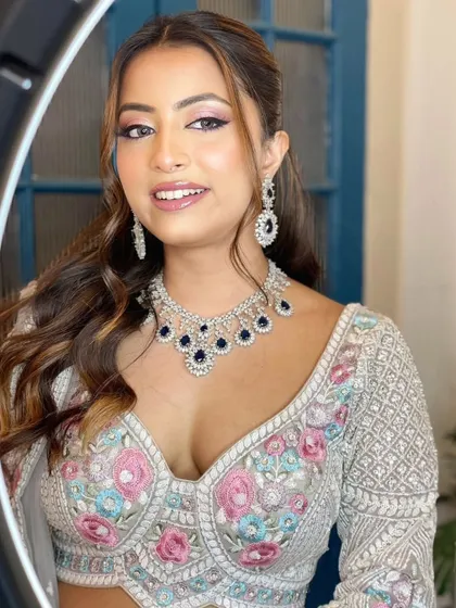 A close-up shot framed by a ring light, highlighting a gorgeous American diamond and sapphire necklace. This piece adds a pop of deep blue to the floral embroidered blouse.