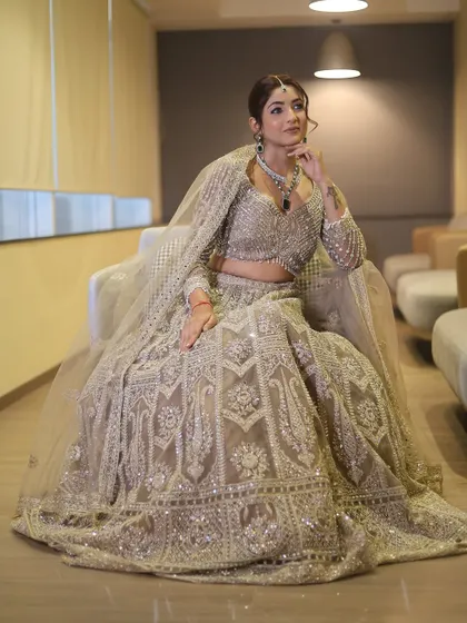 A full-length shot showcasing a magnificent sequined lehenga. The makeup is designed to be just as grand, with a focus on defined eyes and a flawless base that photographs beautifully.