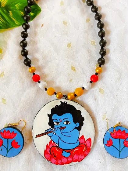 Another view of the Baal Krishna hand-painted terracotta set, showing the black beaded chain. The simple chain helps to draw all the attention to the detailed pendant.