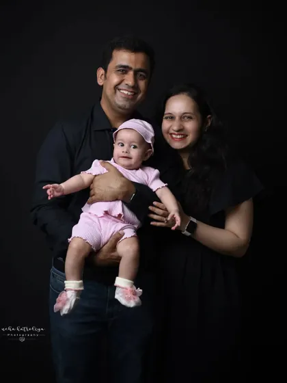 A classic family portrait against a dark backdrop. The simple background and coordinated dark clothing ensure that the family's happy faces are the main focus of the photograph.