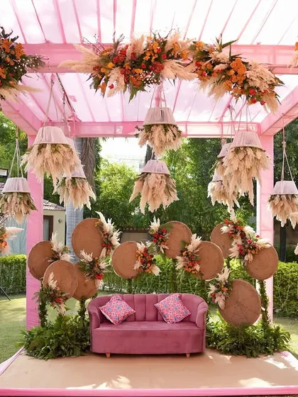 The full view of the unique pink and terracotta Mehendi stage, showcasing the hanging lampshades and pampas grass details that make the decor stand out.