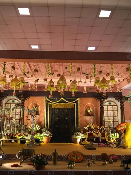 For this naming ceremony, we designed a stage that felt like stepping into a South Indian village home from the 1990s. The setup features a traditional wooden door, intricate pillars, and authentic decor elements like brass vessels and a gramophone.