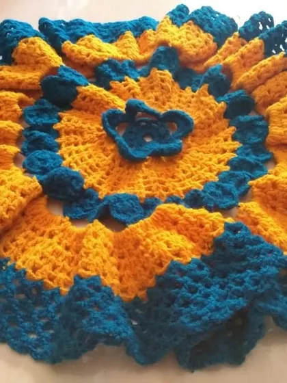 A beautiful dress for a deity idol, crafted in vibrant yellow and blue with a ruffled, layered design.