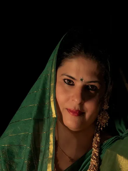 A dramatic, low-light shot in a green silk saree for a Diwali-themed shoot. The head drape adds a touch of traditional mystique.