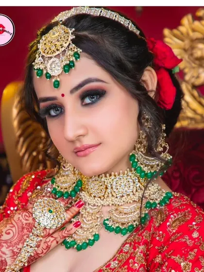 A close-up of a bride wearing a beautiful Kundan and emerald set. The red roses in her hair add a touch of classic romance to the look.