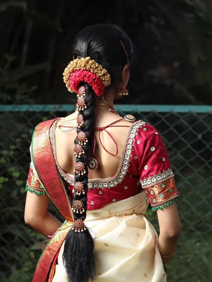 A detailed look at a traditional South Indian bridal hairstyle. The braid is adorned with intricate accessories, a skill that is essential for any bridal artist.