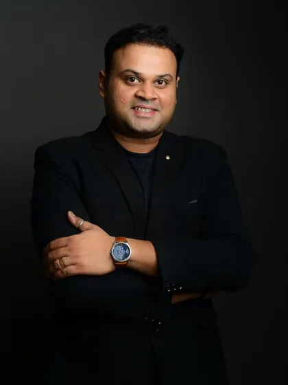 A classic corporate headshot against a dark grey background. The focus is entirely on the subject's friendly and professional expression.