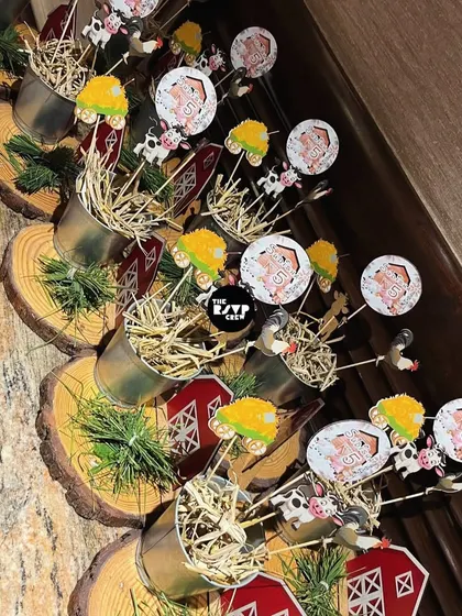 Adorable farm-themed centerpieces with mini barns, tractors, and cows, placed in small buckets on wood slices.