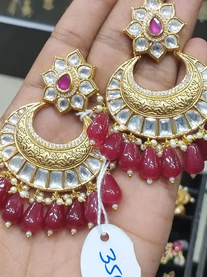 A pair of beautiful Kundan chandbalis with ruby-coloured bead drops. This is a classic design that is always a favourite for festive occasions.