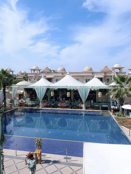 A wide shot of the poolside venue, showing the elegant white tents and aqua-draped canopies that created a chic and comfortable environment for the daytime celebration.