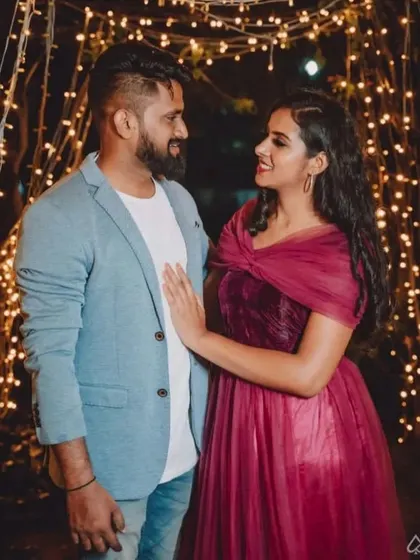 A romantic pre-wedding photo under fairy lights. The client wears our elegant maroon gown with a draped bodice.
