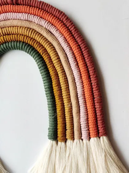 A close-up of the beautiful, earthy color palette of this custom rainbow wall hanging.