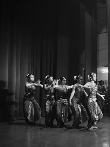 A black and white photograph capturing the timeless elegance of Bharatanatyam. The synchronized movement of the dancers creates a beautiful visual rhythm.