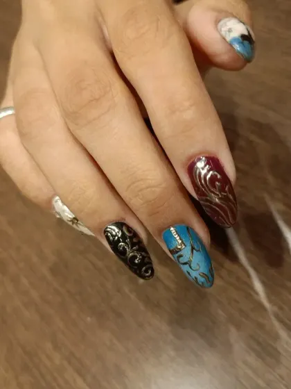 A different angle of the "Howl's Moving Castle" inspired nails, showing the combination of character art and abstract patterns in black, blue, and burgundy.